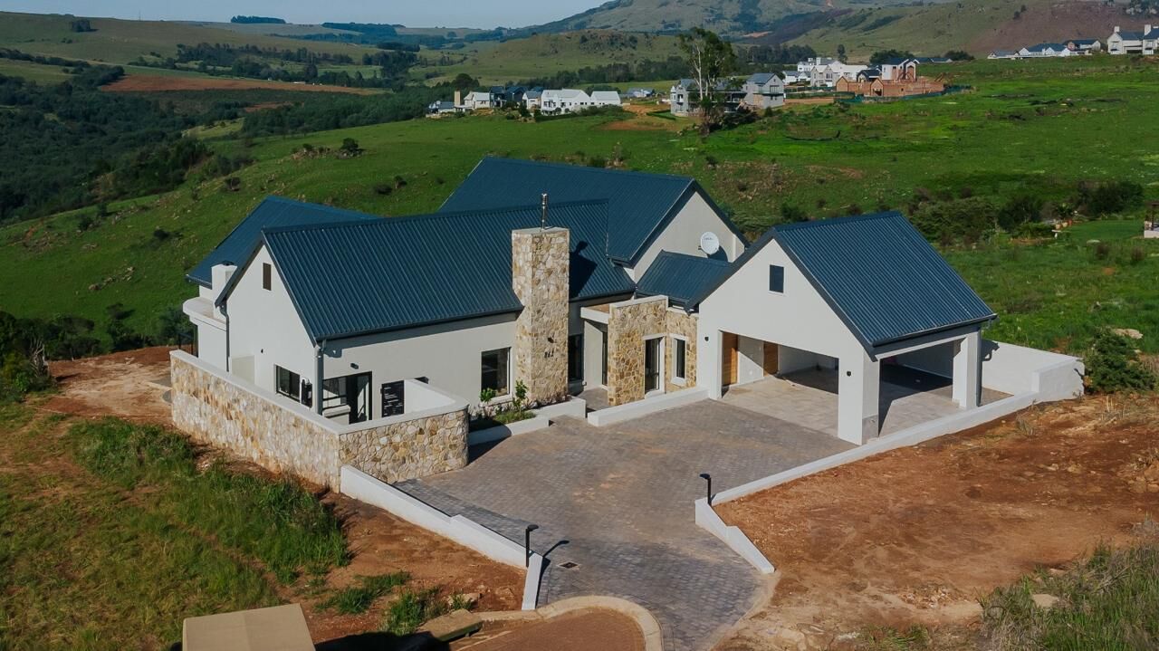 Aerial view of the house with its stone chimney and carport on the hillside